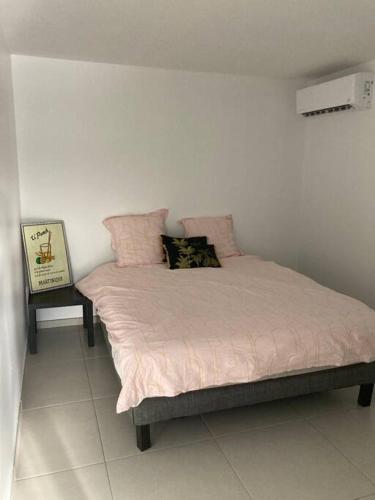 勒拉芒坦KAZ'ANTILLAISE APPT AVEC PISCINE TI MAEVA 3/4P. LE LAMENTIN的一间卧室配有一张带粉色床单和枕头的床。
