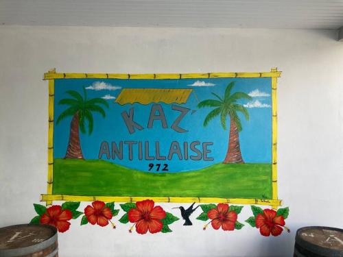 勒拉芒坦KAZ'ANTILLAISE APPT AVEC PISCINE TI MAEVA 3/4P. LE LAMENTIN的棕榈树和鲜花的墙上的标志