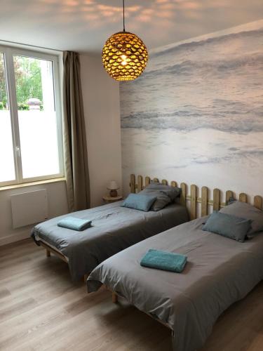 乌尔加特L'Air de la Mer, 2 chambres, 50m plage, parking的卧室内的两张床,墙上有绘画作品