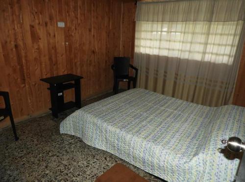 圣罗莎德卡瓦尔Hostal San Ramon的一间卧室配有一张床、一张桌子和一个窗户。
