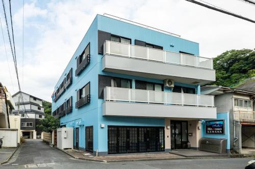 KawanaMR. TOMO KAWANA的蓝色的建筑,设有白色阳台,位于街道上