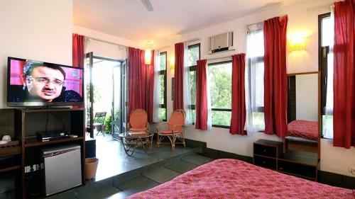 新德里B十九住宿加早餐旅馆的一间卧室设有一张床、一台电视和窗户。