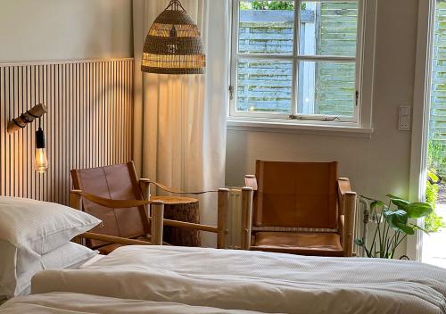 斯诺厄拜克Hotel Blomme's Place的一间卧室配有两把椅子、一张床和窗户