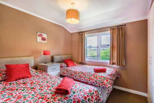 谢伯恩Poppy Lodge的一间卧室配有两张带红色枕头的床和窗户。