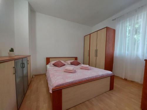 UbliApartman Nora的一间卧室配有一张带粉色床单的床和橱柜。