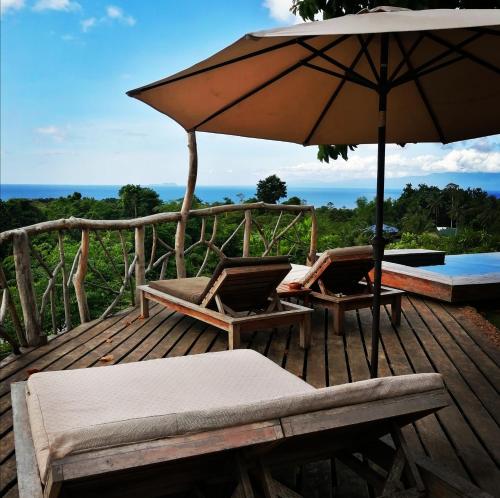 锡基霍尔Nakabalo Guesthouse & Restaurant的木制甲板配有两把椅子和一把伞