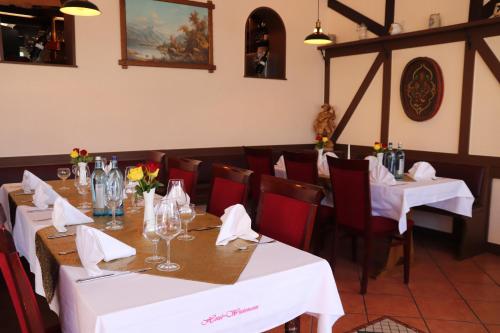 金斯海姆-古斯塔夫斯堡韦恩豪斯威德曼酒店的用餐室配有白色的桌子和红色的椅子