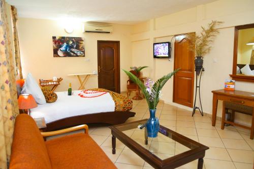 阿克拉Coconut Grove Regency Hotel的酒店客房配有床、沙发和桌子。