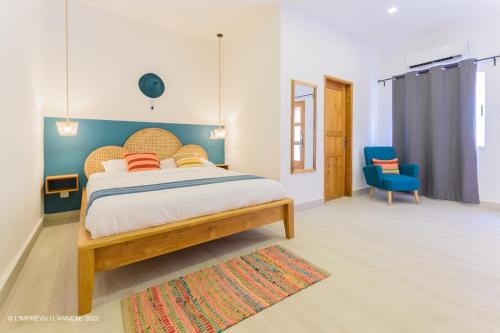 科托努L'imprévu L'annexe的一间卧室配有一张大床和一张蓝色椅子