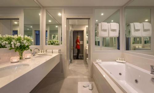 利默里克城堡公园酒店的大型白色浴室设有两个盥洗盆和一个浴缸。