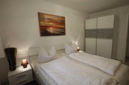 巴贝Haus Meeresblick - Ferienwohnung Ostseeperle A 0.13 (Ref. 128670)的卧室配有白色的床和墙上的绘画作品