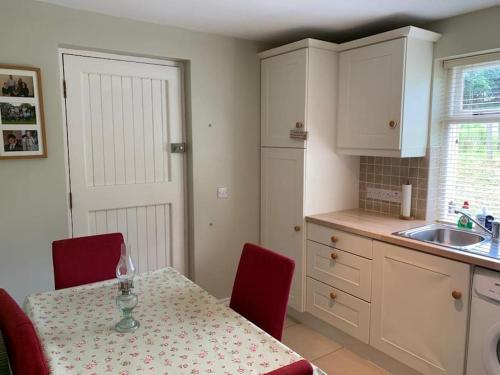 莱特肯尼Butler's Cottage, Letterkenny的一间带红色椅子的桌子的厨房和一间带白色橱柜的厨房
