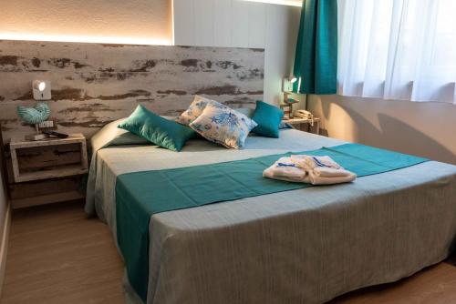 费拉约港阿葵玛莉娜酒店的一间卧室配有一张大床,配有绿色的床单和蓝色的枕头
