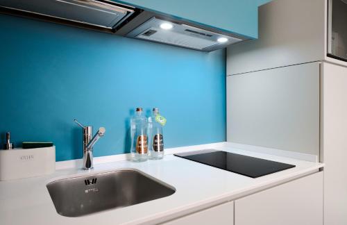 米兰DONATELLO11 Milan apartments的厨房设有水槽和蓝色的墙壁