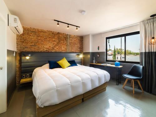 瓜达拉哈拉Hotel NEXT的一间卧室设有一张带砖墙的大床