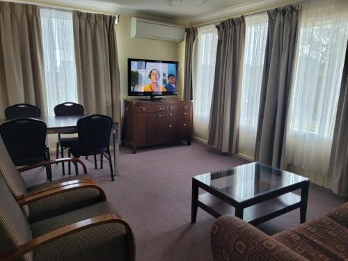 奥伯伦提塔尼亚汽车旅馆的客厅配有电视和桌椅