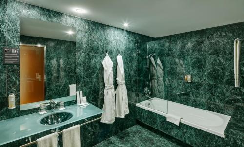 里瓦斯-巴西亚马德里德塞尔科蒂尔AB里瓦斯酒店的一间带水槽、浴缸和镜子的浴室