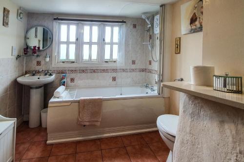 惠灵顿Magnolia Cottage的带浴缸、卫生间和盥洗盆的浴室