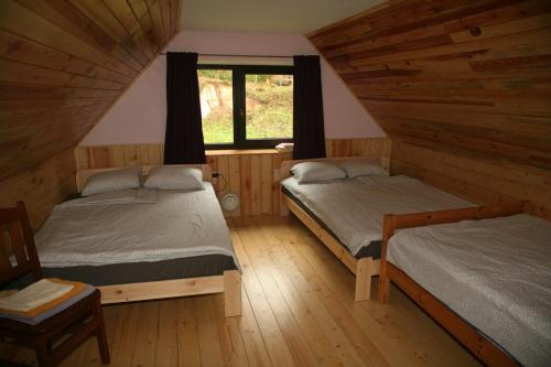 LiepaGRĪVIŅU pirts的小木屋内的两张床,设有窗户
