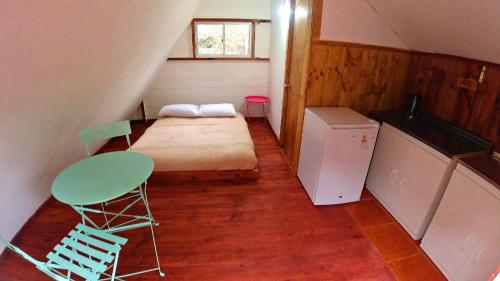 梅利皮亚Lodge Spa Melipilla的小房间设有床、桌子和冰箱