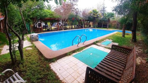 梅利皮亚Lodge Spa Melipilla的庭院内带长凳的游泳池
