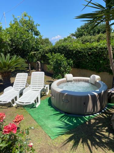 特罗佩阿Villa Saturno的庭院内的热水浴池,配有两把草坪椅