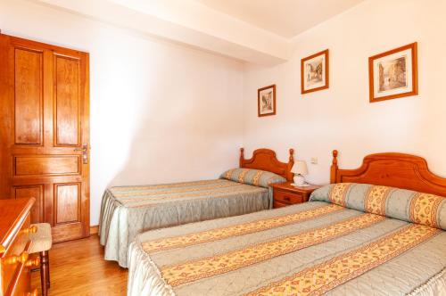 Quintana de LlanesCasa Enrique en el oriente de Asturias的配有白色墙壁和木地板的客房内的两张床