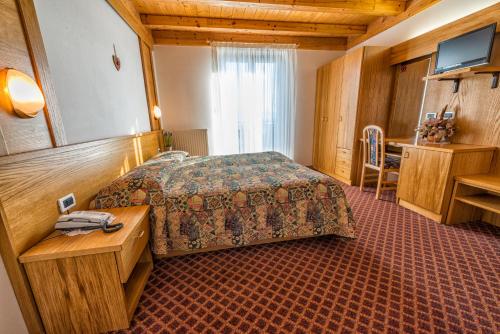 马洛斯科La Montanina Hotel in Val di Non的酒店客房配有一张床铺和一张桌子。