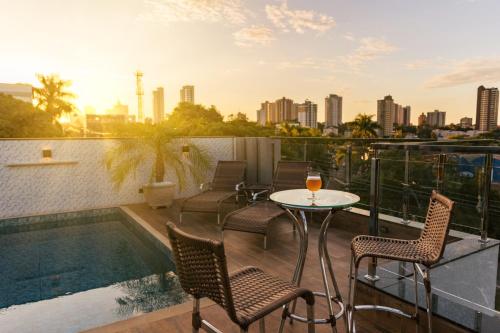 伊瓜苏TuCasa Flats - Viva uma experiência de morador!的一个带桌椅的阳台和一个游泳池