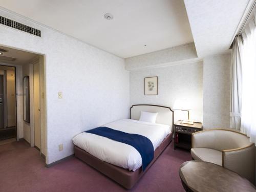神户神户阿里斯顿酒店的一间卧室配有一张床、一张桌子和一把椅子
