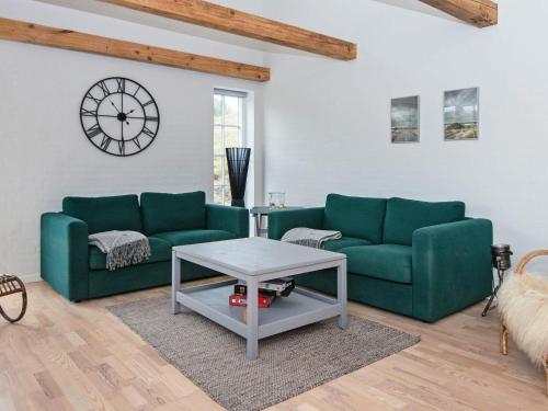 凡岛4 person holiday home in Fan的客厅配有两张绿色沙发和一个时钟