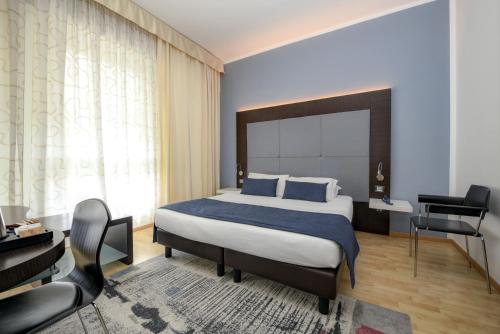 代森扎诺-德尔加达城市酒店的一间卧室配有一张床、一张桌子和一把椅子
