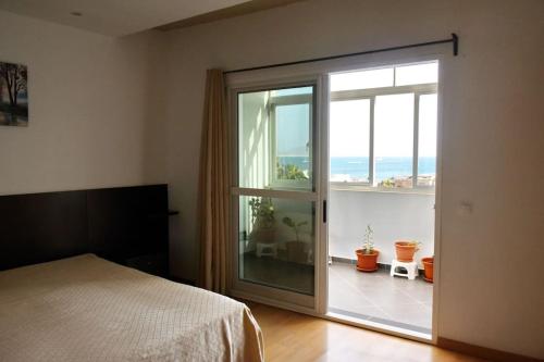 萨尔雷Apartamento moderno com vista para o mar的卧室设有滑动玻璃门,可通往阳台