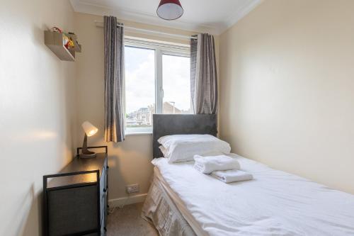 赫尔Hullidays East Modern Detached 3 Bed House的一间卧室配有一张带白色床单的床和一扇窗户。