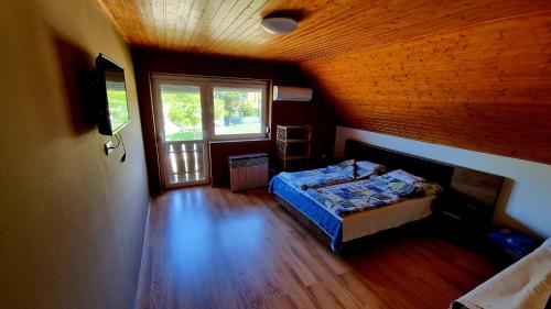 希欧福克Relax Apartman Siófok-Sóstó的一间设有一张床铺的卧室,位于一个拥有木制天花板的房间