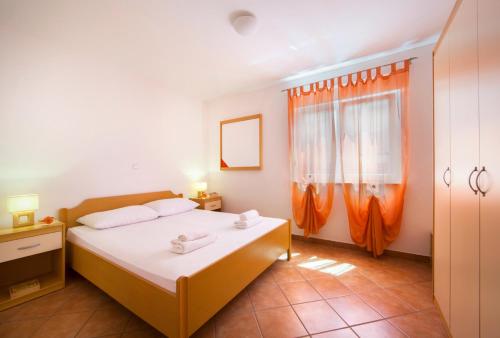科马尔纳多利安别墅公寓的一间卧室配有白色床单和橙色窗帘
