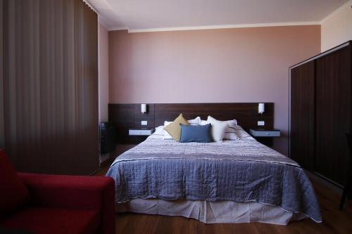马拉圭Hotel Terra Patagonia的一间卧室配有一张床和一张红色椅子