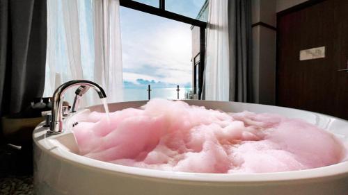 Ban Thong Yangสิชลเตโซโร的窗户前装满粉红色泡沫的浴缸