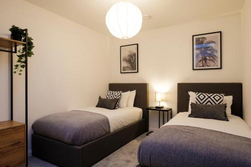 赛伦塞斯特Glevum Lodge - 2 Bedroom Town Centre Apartment的一间卧室配有两张床和吊灯。