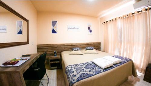 Telêmaco BorbaOpen Hotel的一间卧室配有床和一张带毛巾的书桌