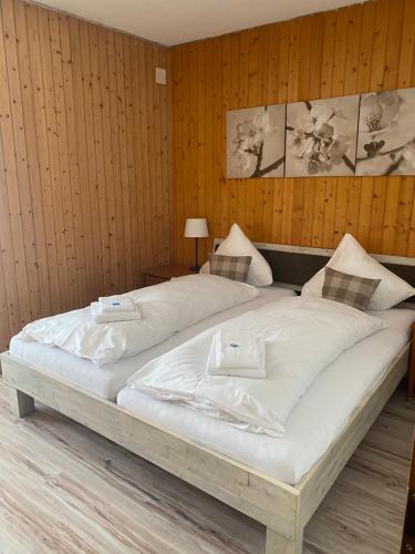 迈林根哈斯里山林小屋的一张白色大床,位于带木墙的房间