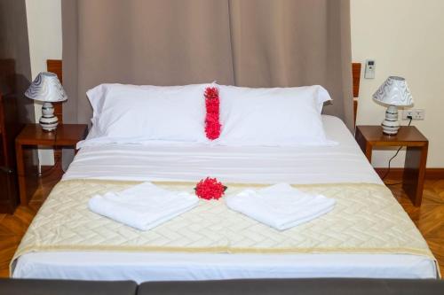 维多利亚Will's Sea View Apartments的一张带两条毛巾的白色床和一朵红花