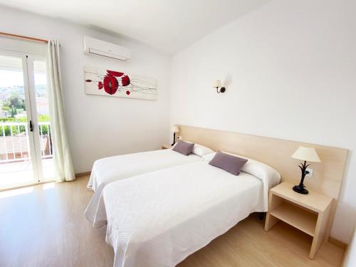 佩尼斯科拉Habitaciones Camping Ferrer的一间白色卧室,配有两张床和窗户
