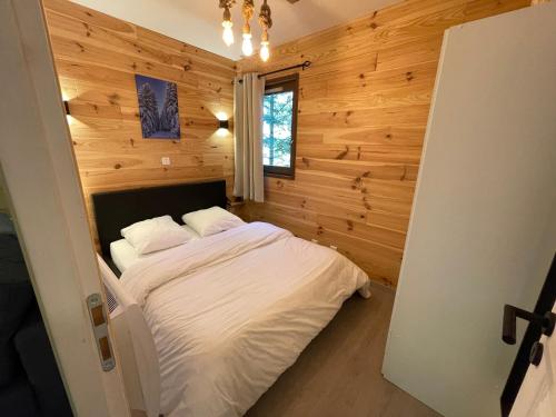 欧龙Cosy appartement au calme à deux pas du centre的卧室配有一张床铺,位于带木墙的房间内