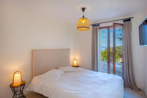 利勒鲁斯Villa bodri, maison en pierre avec vue mer et piscine chauffée的一间卧室配有一张床、两盏灯和一个窗户。