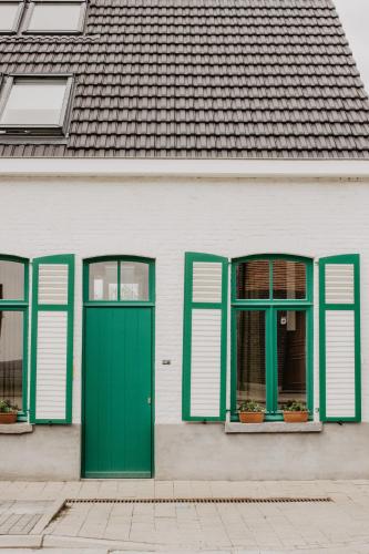 圣劳伦斯Huisje Nummer Tien的白色的房子,设有绿色的门和窗户
