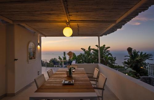 阿纳卡普里Capri Blue Luxury Villa Le Tre Monelle的阳台上的木桌和椅子,享有日落美景