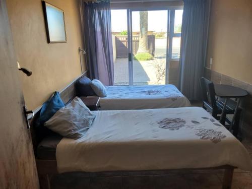 鲸湾港Namibia Skipper Services的带阳台的酒店客房内的两张床