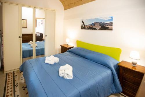 特拉帕尼伐戴拉250公寓的一间卧室,在蓝色的床上配有2条毛巾