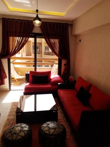 马拉喀什Agréable appartement au coeur de Guéliz, Marrakech的客厅配有红色家具和大窗户